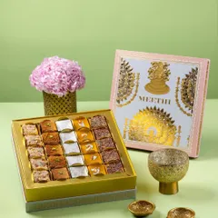 A beautifully designed mithai box from Meethi India, styled with fresh flowers and brass diyas. The light green background gives this festive shot a soft and premium feel.