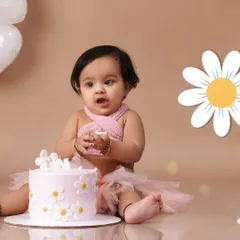 A sweet baby girl in a pink tutu celebrates her first birthday with a daisy-themed cake smash session.