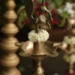 A traditional brass diya featuring a peacock motif, adorned with a string of fresh jasmine flowers. It’s these small, cultural details that bring soul to a wedding design.