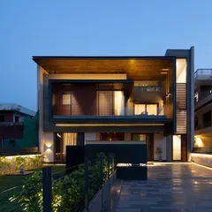 A dusk view of a private residence where the lighting design begins to take effect. The combination of warm interior light spilling out and the targeted exterior uplighting creates a beautiful, layered composition.