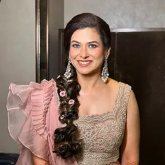 A portrait of pure elegance. This look features a dewy, fresh base, defined eyes, and a soft pink lip, all designed to complement her ruffled saree and radiant smile.