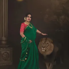 In this moody, painterly portrait, a mother-to-be stands beside a lion under a full moon. The deep green saree and dramatic lighting evoke a sense of mystery and ancient power, transforming a maternity photo into a mythological narrative.