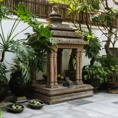A miniaturized replica of a temple from Bhubaneshwar's Lingaraj Temple, placed within the courtyard. This, along with other traditional vessels repurposed as planters, adds character and a sense of sacred history to the space.