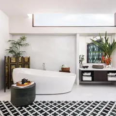 This spacious bathroom is designed for ultimate relaxation. A freestanding tub sits under a skylight, bathing the room in natural light. The patterned floor tiles and the custom-designed green door with mother-of-pearl inlays add unique, artistic touches to the space.