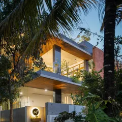 The arrival experience at the 'House of Greens' is designed to be a journey. You pass under a mango tree and through a landscaped nook, with a cantilevered portico guiding you toward the entrance, immediately immersing you in a serene, green environment.