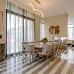 Dine in style in this peaceful dining area where grey meets beige. The striped marble floor, quilted chairs with gold-finished legs, and a modern light fixture create a perfect recipe of minimalism and warmth.