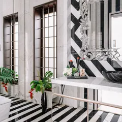 I love to play with bold patterns. In this powder room, we used black and white marble to create a dramatic piano-key striped floor and a chevron-patterned wall. The ornate silver mirror adds a touch of glamour to the graphic design.