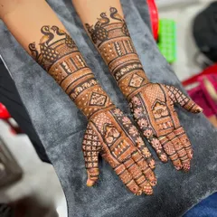 A beautiful example of a full-arm bridal design. The pattern includes rows of peacocks on the forearm and a mix of jaali and floral work on the hands.