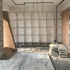 Work in progress at one of our sites, where the framework for a large shelving unit is being installed and the first marble slab is laid. This image shows the raw, foundational stage where the structural elements of our design begin to take physical form.