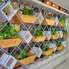 For this office, I created a unique plant partition that serves as both a stunning design feature and a natural space divider. The geometric metal frame combined with wooden and white planter boxes adds a modern, artistic touch to the workplace.