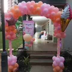 An outdoor entrance arch for a candy-themed party. The peach and pink balloons, along with an ice cream foil balloon, create a sweet welcome for guests.