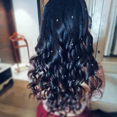 A romantic half-up, half-down style featuring voluminous curls. The hair is adorned with scattered pearl pins, adding a touch of subtle sparkle for a reception or cocktail party.