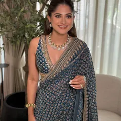 A smiling portrait of the guest, showcasing her classic makeup look with a simple bindi and soft lip color.