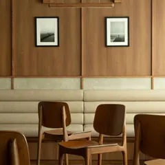 The linear seating arrangement at QBF Coffee, with continuous upholstered benches against wood-paneled walls. This efficient and elegant solution maximizes space while maintaining a clean, uncluttered aesthetic.