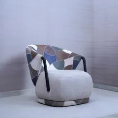 This accent chair is a testament to our love for materials, featuring a unique patchwork of leather and fabric in earthy tones. The design combines a plush, comfortable seat with a sculptural, curved back and textured armrests, making it a standout piece in any room.