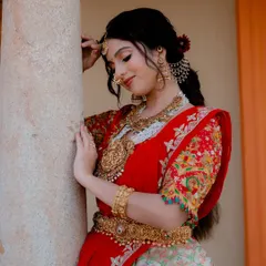 A quiet, contemplative bridal portrait. The soft pose and gentle light create a serene mood, drawing attention to the fine details of her outfit and jewelry.