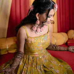 A happy Mehendi bride admiring her intricate henna design. Her makeup was kept fresh and natural to match the daytime event.