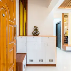 A bright and functional foyer design with a white high-gloss shoe cabinet that includes a built-in wooden seater. The yellow fluted panel adds a pop of color and texture to the entryway.