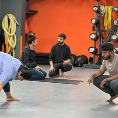 Personal training with us means getting detailed, one-on-one attention. Here, our trainers are observing a client's form in a forward fold, providing corrections to ensure she gets the most out of the stretch safely. This personalized guidance is key to achieving specific fitness and recovery goals.