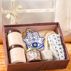 For a sibling who appreciates wellness and good vibes, this Rakhi hamper includes scented candles, ceramic jars of healthy treats, printed coffee mugs, and a beautiful Hamsa hand ornament for protection.