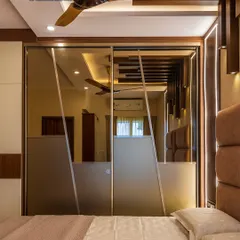 Your bedroom should be your personal sanctuary. We designed this luxurious master bedroom with a stunning lacquered glass sliding wardrobe that reflects the room's elegant lighting and plush headboard, creating a space of ultimate comfort and style.