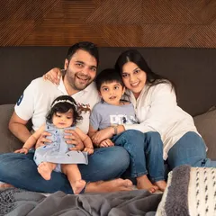 A classic family portrait taken during an in-home session. Sitting together on the bed, this family's comfort and connection are clear, making for a relaxed and natural photo.