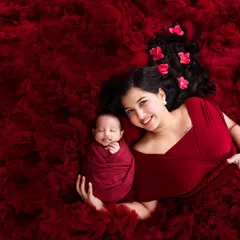 The bond between a mother and her newborn is pure magic. For this shot, we used a flowing red gown and fabric to create a rich, warm bed, capturing a beautiful smile from the little one.