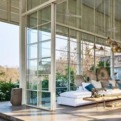 The living pavilion of The Ray Villa features floor-to-ceiling glass walls that slide away, completely opening the space to the elements. This design erases the boundary between the interior and the surrounding tropical landscape.