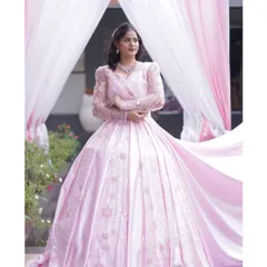 A client looking absolutely beautiful in the pink princess gown. This photo captures the elegance of the embroidered long sleeves and the flattering silhouette against a lovely outdoor backdrop.