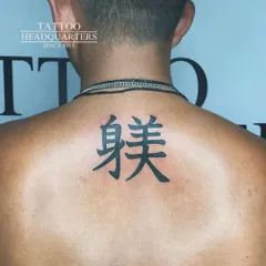 A clean and bold tattoo of Chinese characters on the upper back.