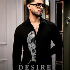 Wearable art for the modern man. This black shirt features a striking abstract face embroidered in geometric lines of silver and gold thread, creating a look that is both artistic and powerful.
