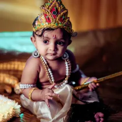 A thoughtful, seated portrait from our Little Krishna series. The composition focuses on the baby's calm demeanor and the rich details of the costume and props, creating a timeless and artistic image.