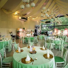 The guest seating area was designed to complement the enchanted garden theme. Tables were dressed in soft green linens, with simple centerpieces that allowed the grand stage and ceiling decor to be the main focus.