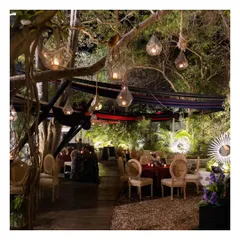 An enchanting evening setup at the Garden of Five Senses, with hanging lanterns and elegantly set tables. This showcases the magical ambiance our team helps create in collaboration with top decor vendors.