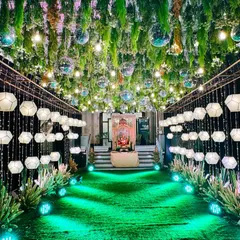 I created this spectacular walkway for a Sangeet by hanging hundreds of geometric lanterns and disco balls from a ceiling of lush greenery. The green uplighting on the path adds to the dramatic, party-ready feel.