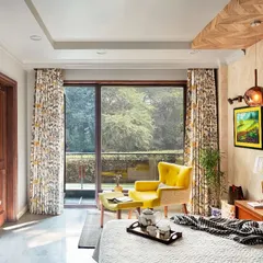 The bedroom at Ridge View is personal and expressive. A neutral canvas allows vibrant elements like the canary yellow accent chair to take center stage, while a herringbone wooden panel on the ceiling adds a touch of drama.