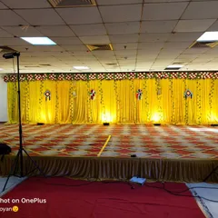A classic Haldi ceremony stage with a bright yellow curtain backdrop. I use simple uplighting to enhance the color and create a focal point for the rituals, with speakers placed on the sides for music.