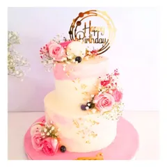 A special birthday cake for a very special mom. This two-tier cake in shades of pink is adorned with fresh roses and baby's breath, creating a classic and heartfelt tribute.