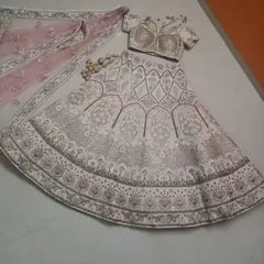 A flat-lay of the complete ivory and pink lehenga set. This view clearly displays the skirt's A-line cut, the blouse design, and the matching embroidered dupatta, helping you visualize the entire ensemble.