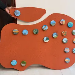 Holding the final piece before installation. You can see the scale of this textured MDF board and the arrangement of the tiny, circular memory paintings.
