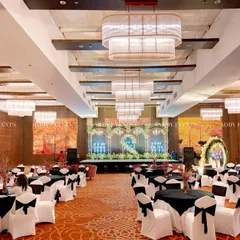 A wide-angle view of a modern Sangeet in a grand ballroom. The image highlights the cohesive black and white theme, from the guest tables to the main stage, under elegant chandeliers.