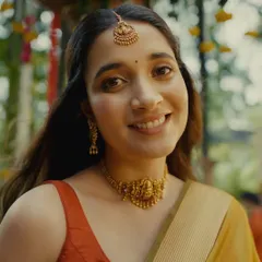 A close-up of a radiant bride from the Kushal's Jewellery campaign. This traditional South Indian bridal look features a classic temple jewellery choker and maang tikka, paired with warm, glowing makeup and a simple bindi.