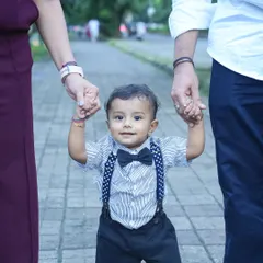 A baby's first steps are a memory a family holds forever. Here, little Krishiv is safely guided by his parents' hands, a simple, powerful image of love and support that defines family photography.