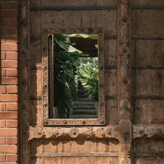 A reclaimed wooden door features a mirror that reflects the garden, cleverly bringing the landscape inside. This detail is part of a larger strategy to ensure every corner of the home has a connection to the green spaces I designed.