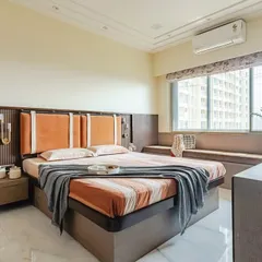 Warmth and comfort define this bedroom. The custom headboard features bold orange upholstered panels set against a dark wood fluted backdrop. A cozy window seat provides extra seating and a place to enjoy the city view.