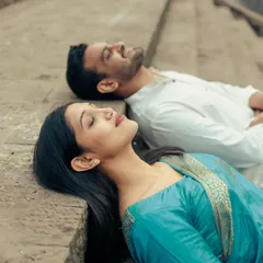 A serene portrait of the couple resting on the stone steps, a quiet moment of togetherness during their traditional pre-wedding shoot.