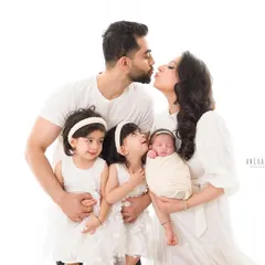 Kisses for mama and the new baby. These are the candid, love-filled moments that make family portraits so special. This image beautifully shows the affection shared between everyone.
