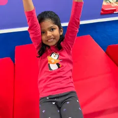 Pure accomplishment and a bright smile. This young gymnast celebrates a successful move, showing the confidence that comes from practice and play.