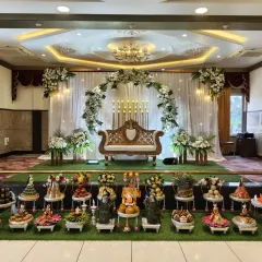 An elegant and modern take on traditional decor for a Half-Saree program. This setup features a full arch of white gerberas and fresh greenery against a clean white drape, with candle-like lighting adding a touch of sophistication.
