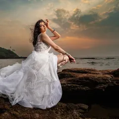 A bridal portrait on the rocks as the sun sets over the ocean. The beautiful colors of the sky and the soft light create a dramatic and romantic mood for this stunning shot.